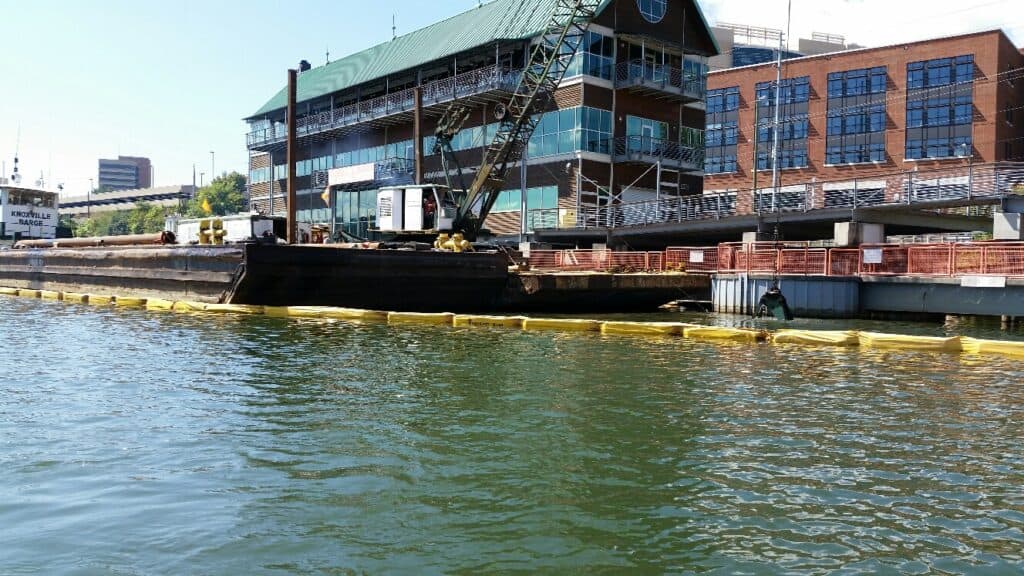 Barge docked at Knoxville waterfront with industrial building backdrop.